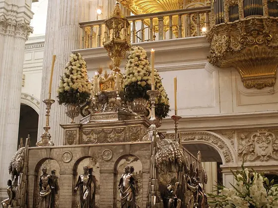 La custodia del Corpus en la Catedral de Granada, de plata y llena de flores blancas, bajo los dorados del retablo.