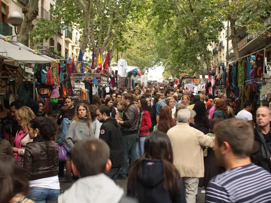 Ribera de Curtidores llena de gente de acera a acera, con los puestos de ropa colgada a los dos lados y los plátanos de sombra por encima.